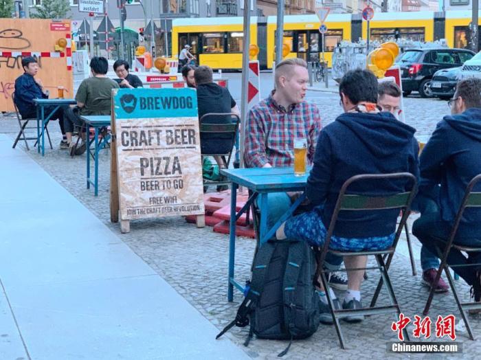 6月3日，柏林市中心一家精酿啤酒吧的顾客坐在街边饮酒。每桌顾客均保持了1.5米以上的距离。 /p中新社记者 彭大伟 摄